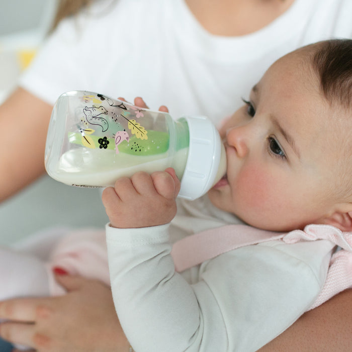 An adult in a white shirt holds a baby drinking from a Dr. Brown’s Natural Flow® Anti-Colic Options+™ Wide-Neck Baby Bottle with Level 1 Slow Flow Nipple, 5oz/150mL, by Dr. Brown’s.