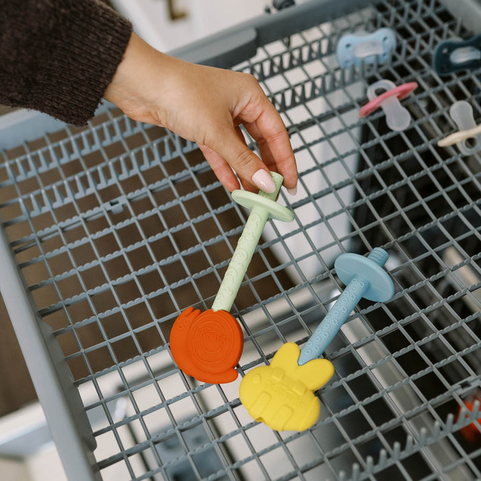 Person putting snail and bee teething tubes into dishwasher